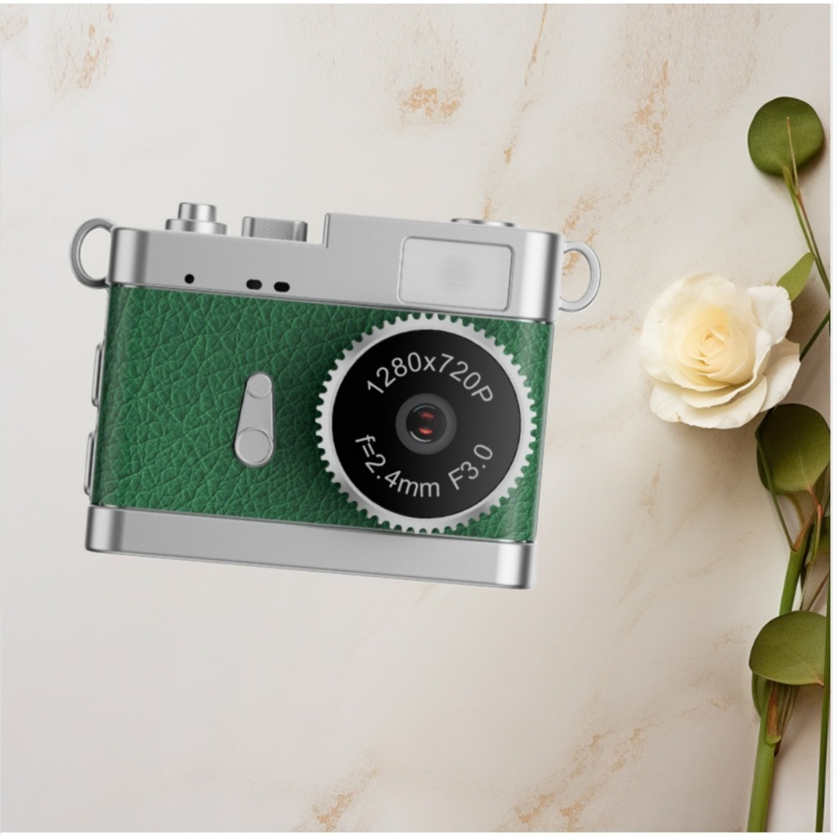 Grüne Retro-Kamera mit silbernen Details auf Marmorfläche, neben einer weißen Rose.