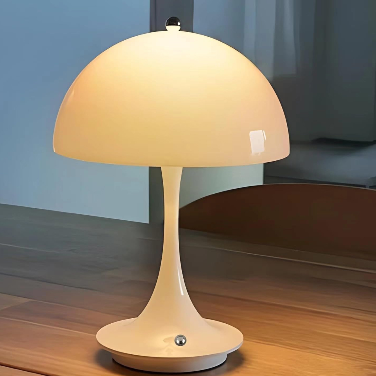 Eine weiße Pilzlampe mit Kuppelschirm steht auf einem Holztisch.