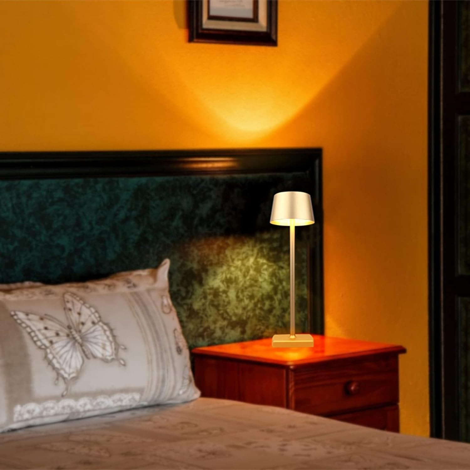 Ein Nachttisch mit einer Lampe, einem Bett mit Schmetterlingskissen.
