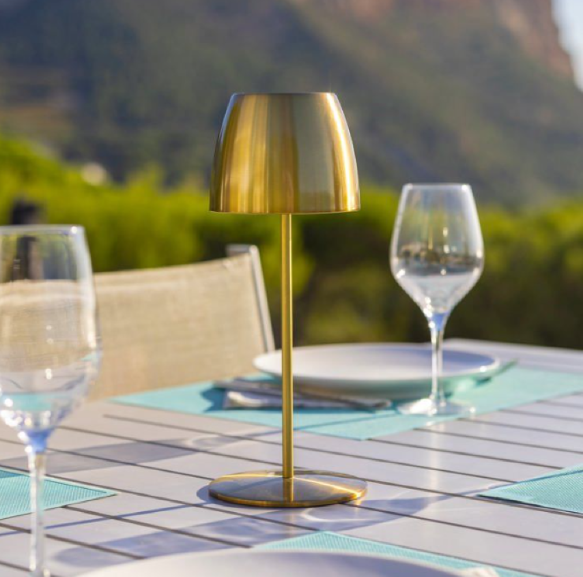 Ein goldener Tisch und zwei Weingläser auf einem Tisch im Freien.
