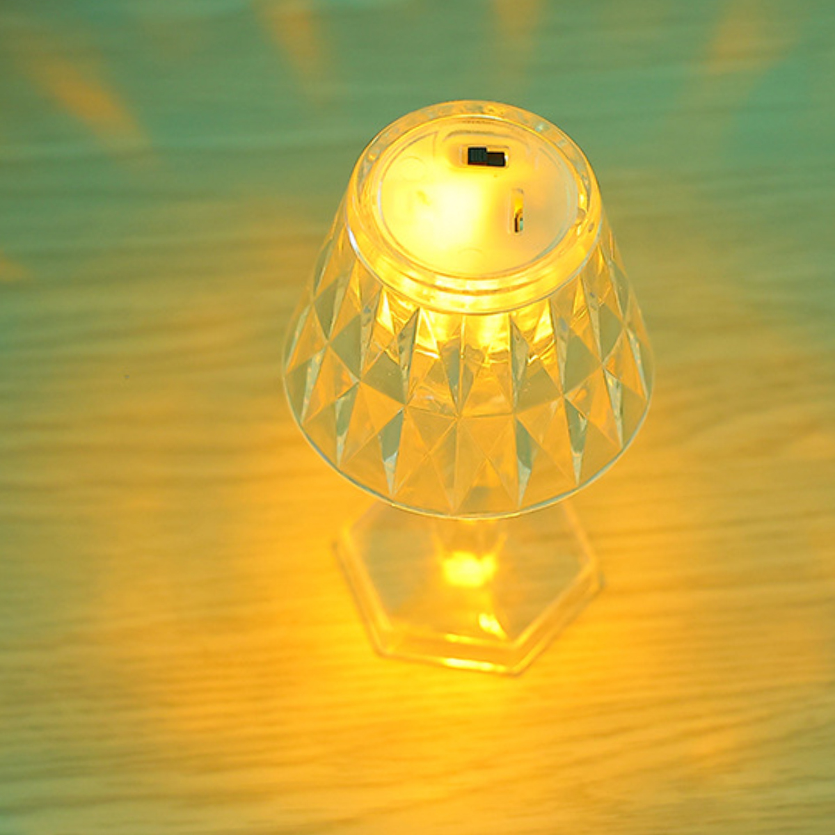 Eine leuchtende, facettierte Tischlampe aus Kristall auf einem Holztisch.