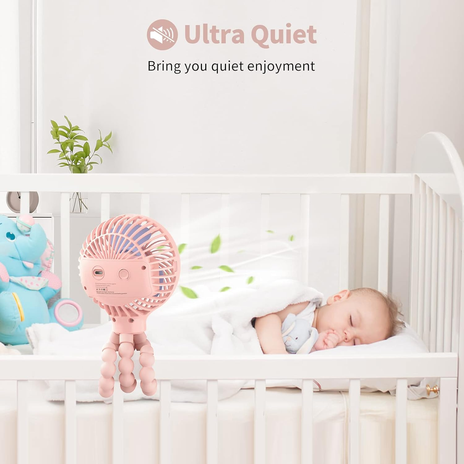 Rosa tragbarer Ventilator klemmt am Kinderbett neben schlafendem Baby und blauem Elefanten.