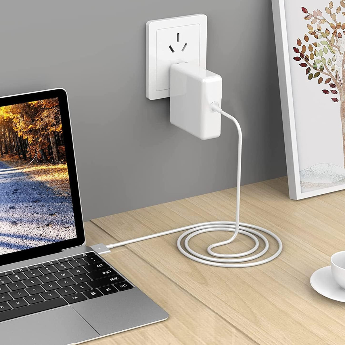 Ein Laptop ist auf einem Holztisch mit einem weißen Ladegerät verbunden.