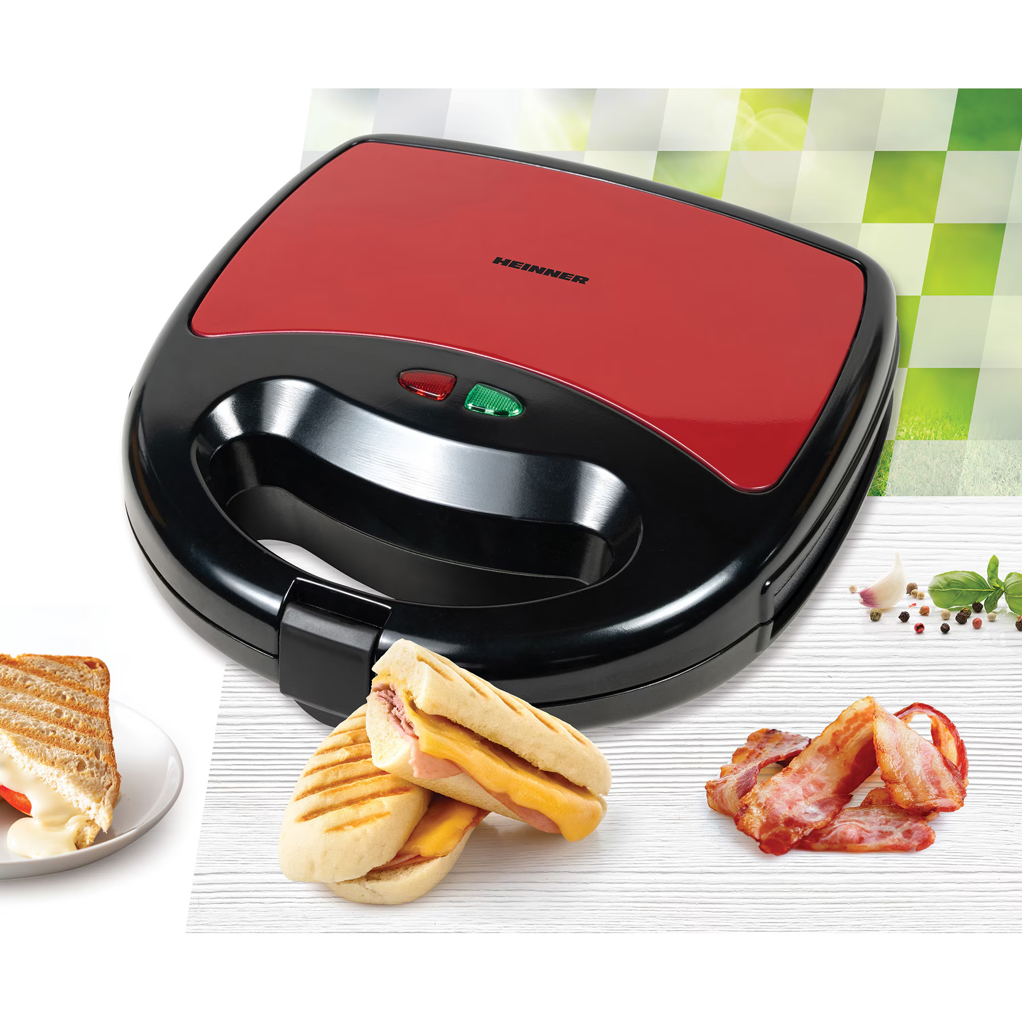 Ein roter und schwarzer Kontaktgrill mit Sandwiches und Speck daneben.