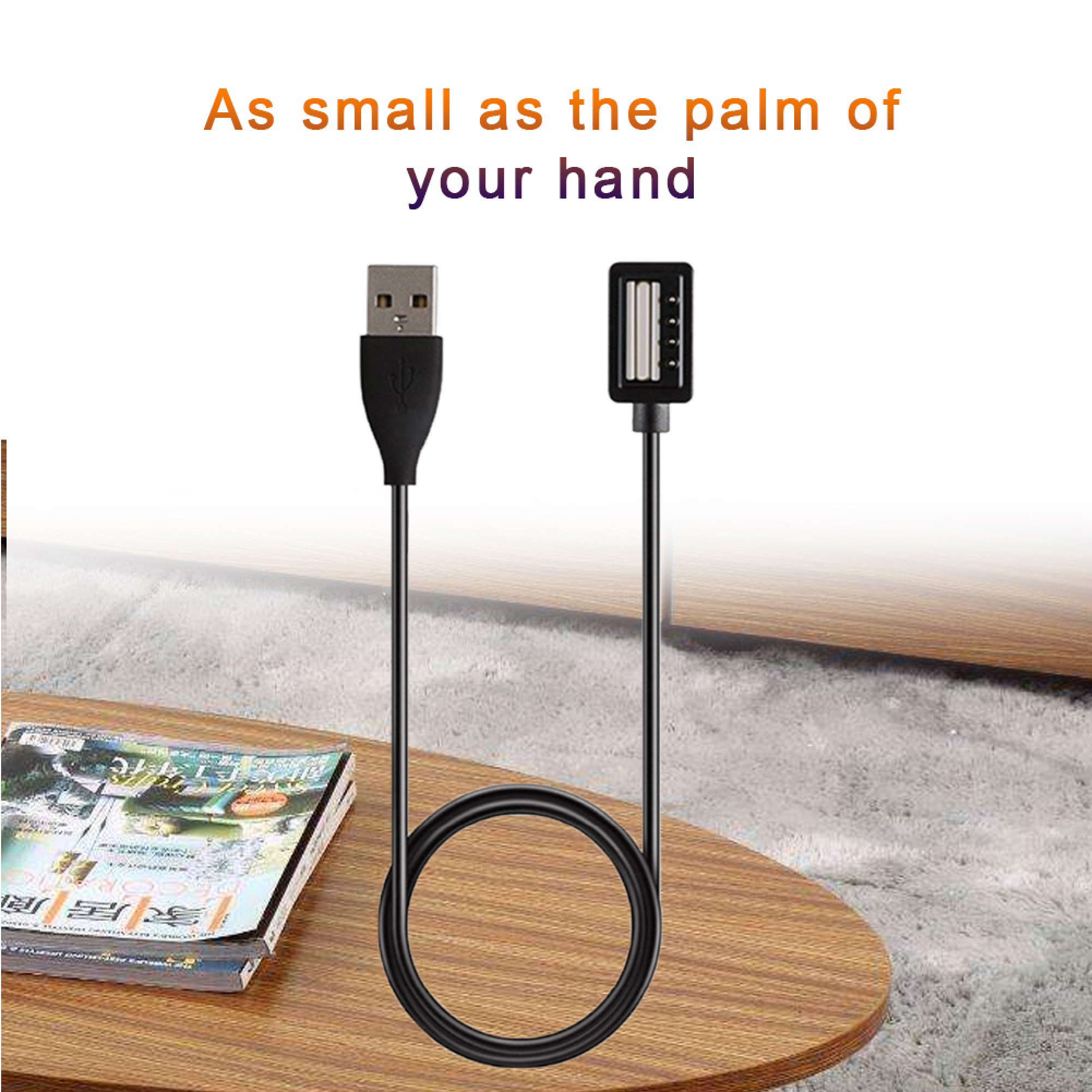 Ein schwarzes USB-Kabel mit zwei Anschlüssen liegt auf einem Holztisch neben Zeitschriften.