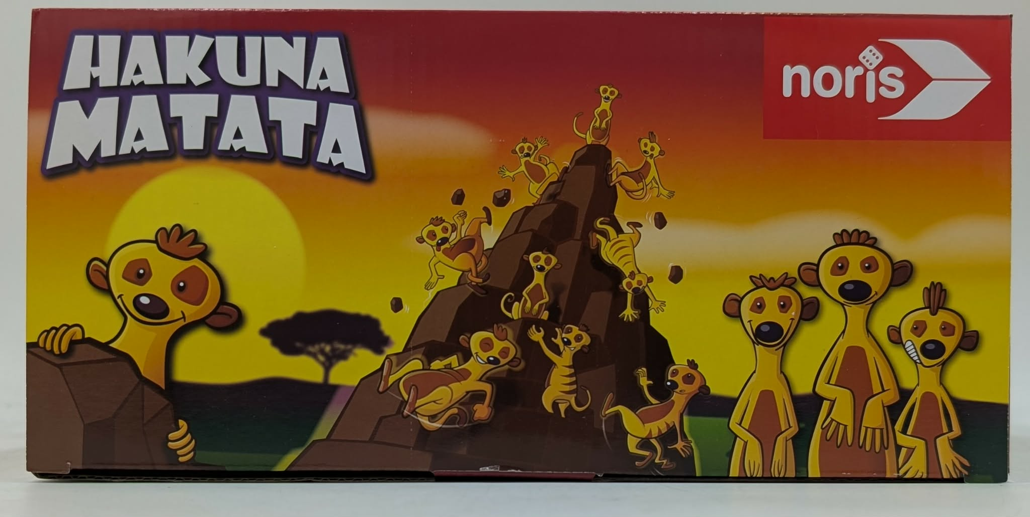 Hakuna Matata Kartonkunst mit Erdmännchen auf einem Felsen bei Sonnenuntergang.