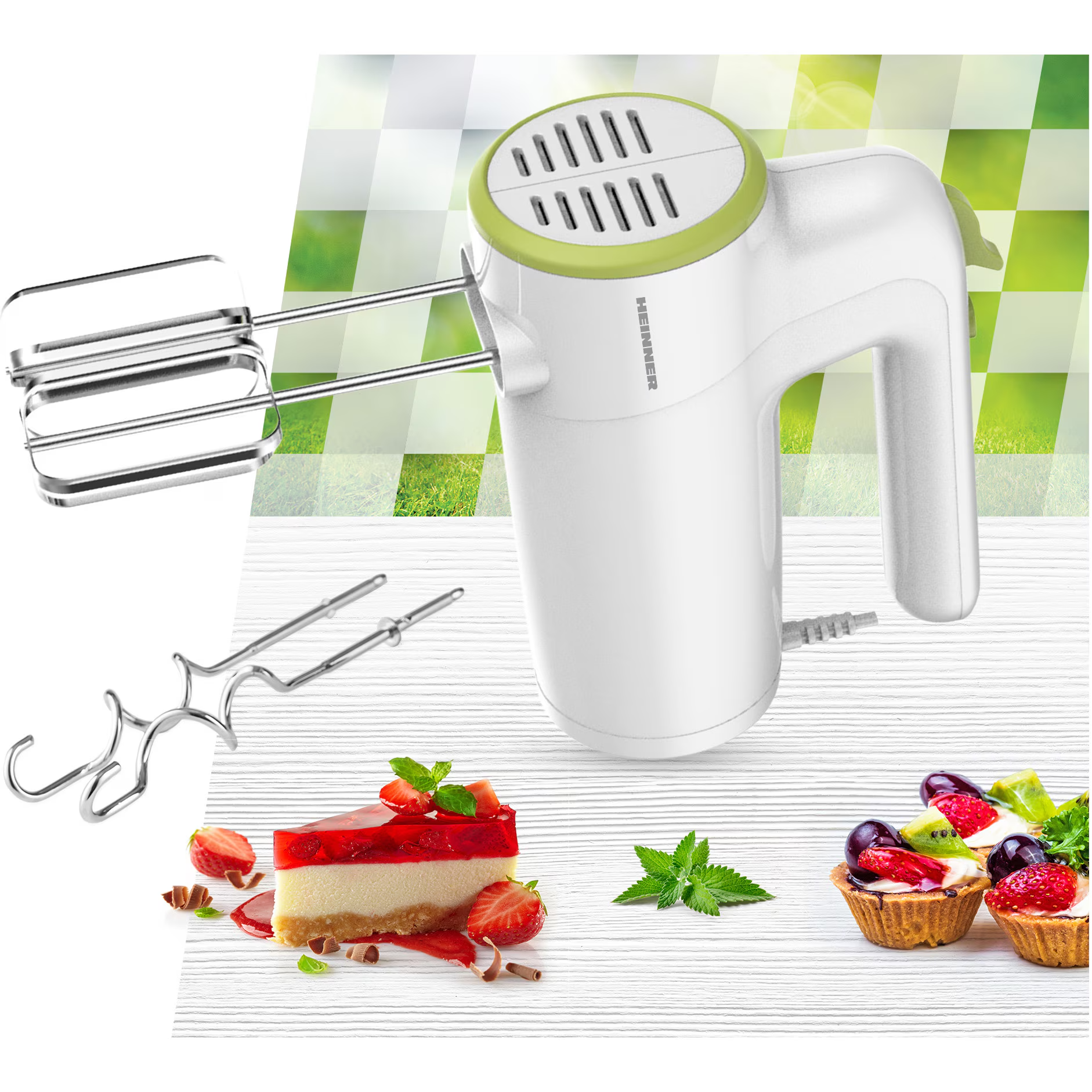 Een witte handmixer met groene accenten, naast gebakjes en fruit.