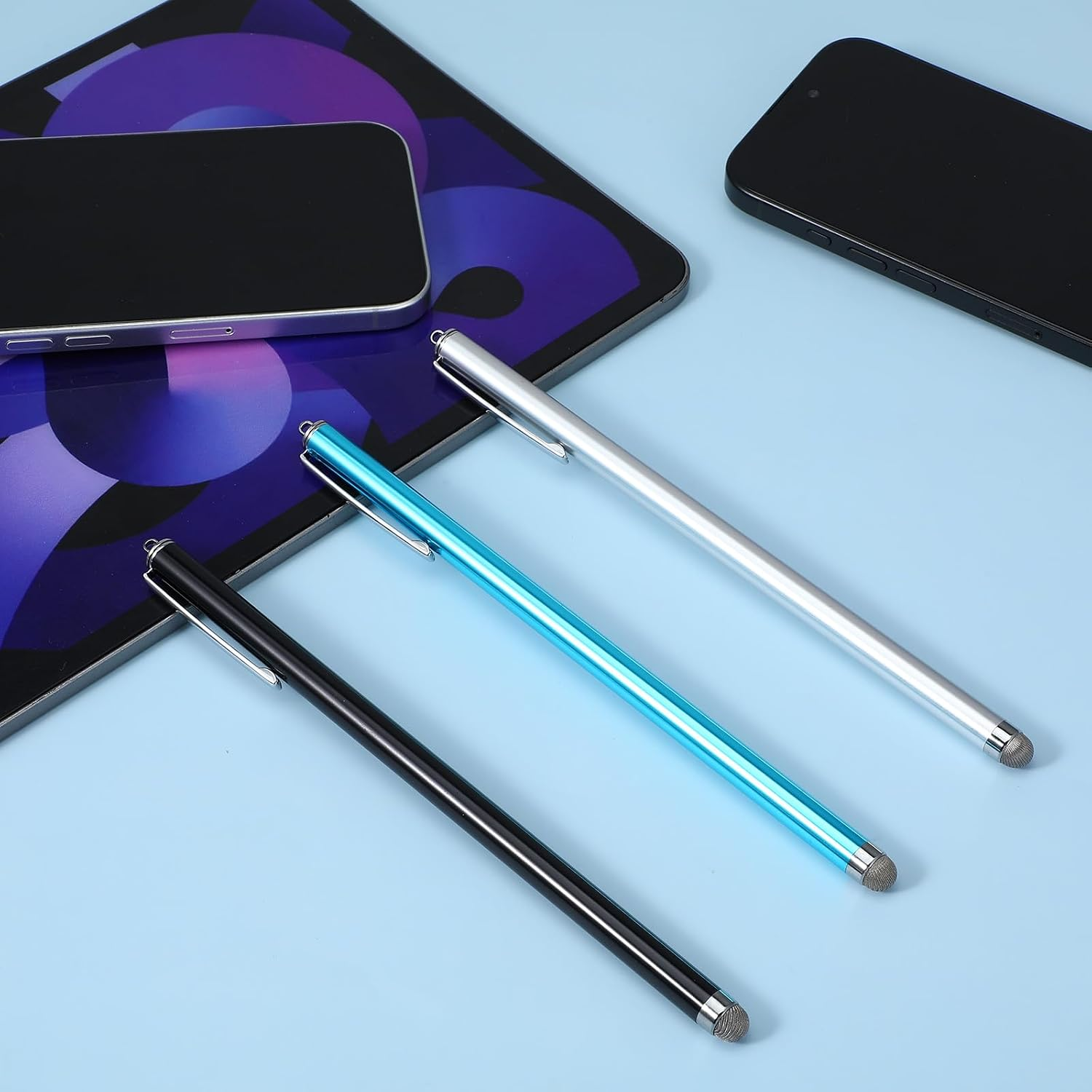 Drei Stifte, schwarz, blau und silber, liegen auf einem Tablet und Handy.