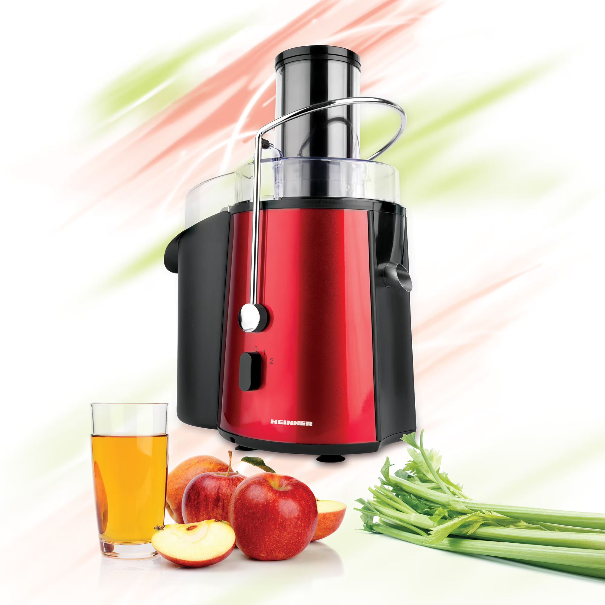 A red juicer with a glass of juice, apples and celery.