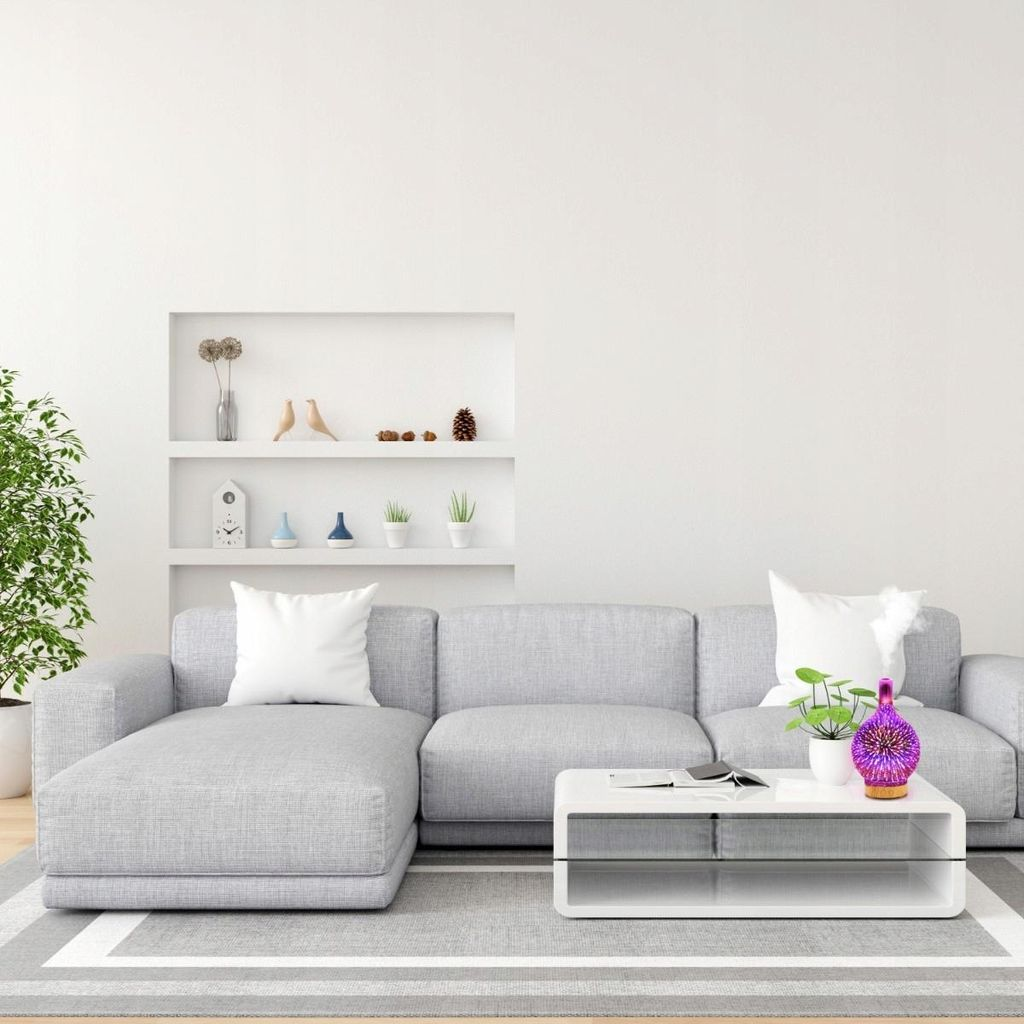 Ein hellgraues Ecksofa mit weißen Kissen vor einem weißen Regal.