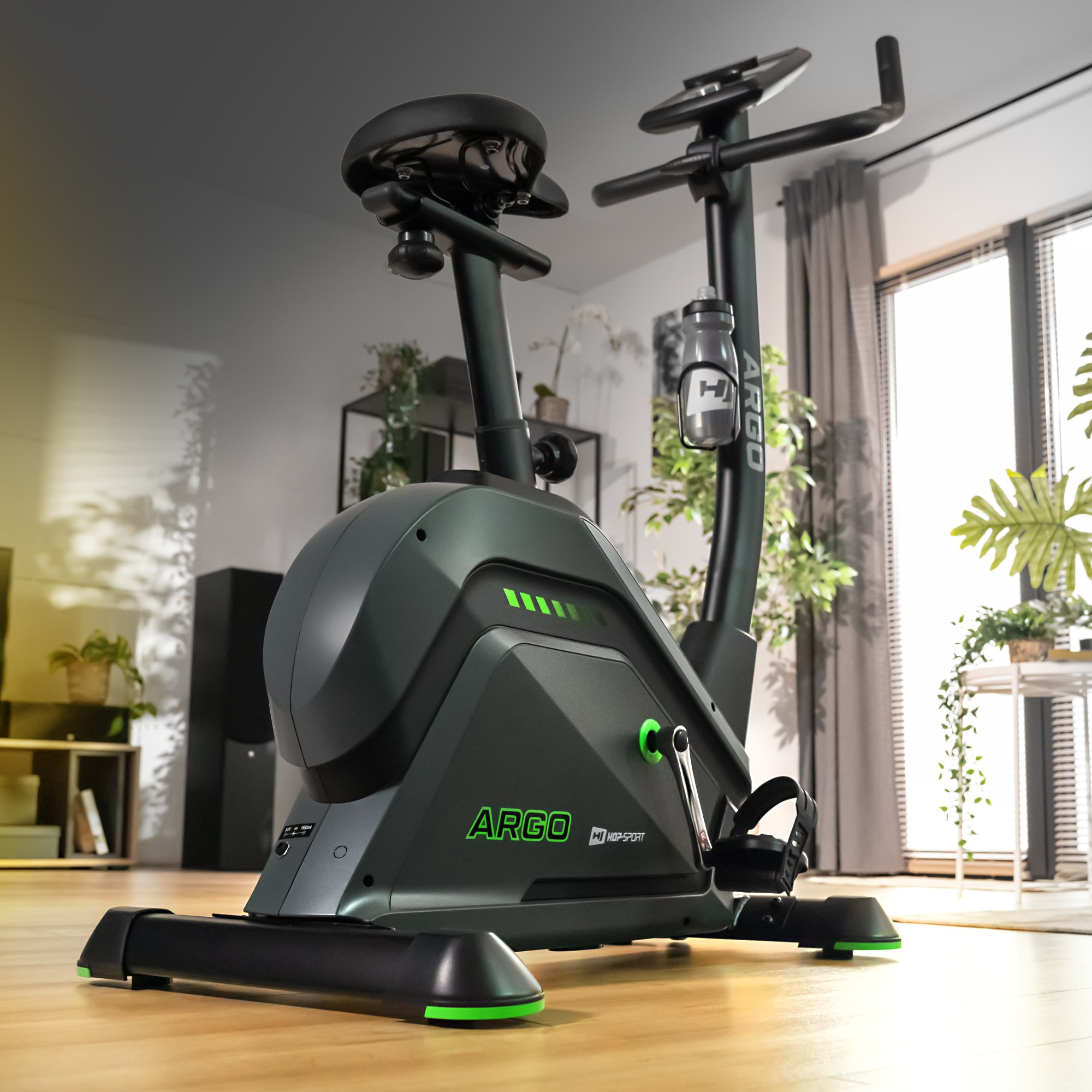 Ein schwarzes Ergometer mit grünen Akzenten steht auf einem Holzboden.