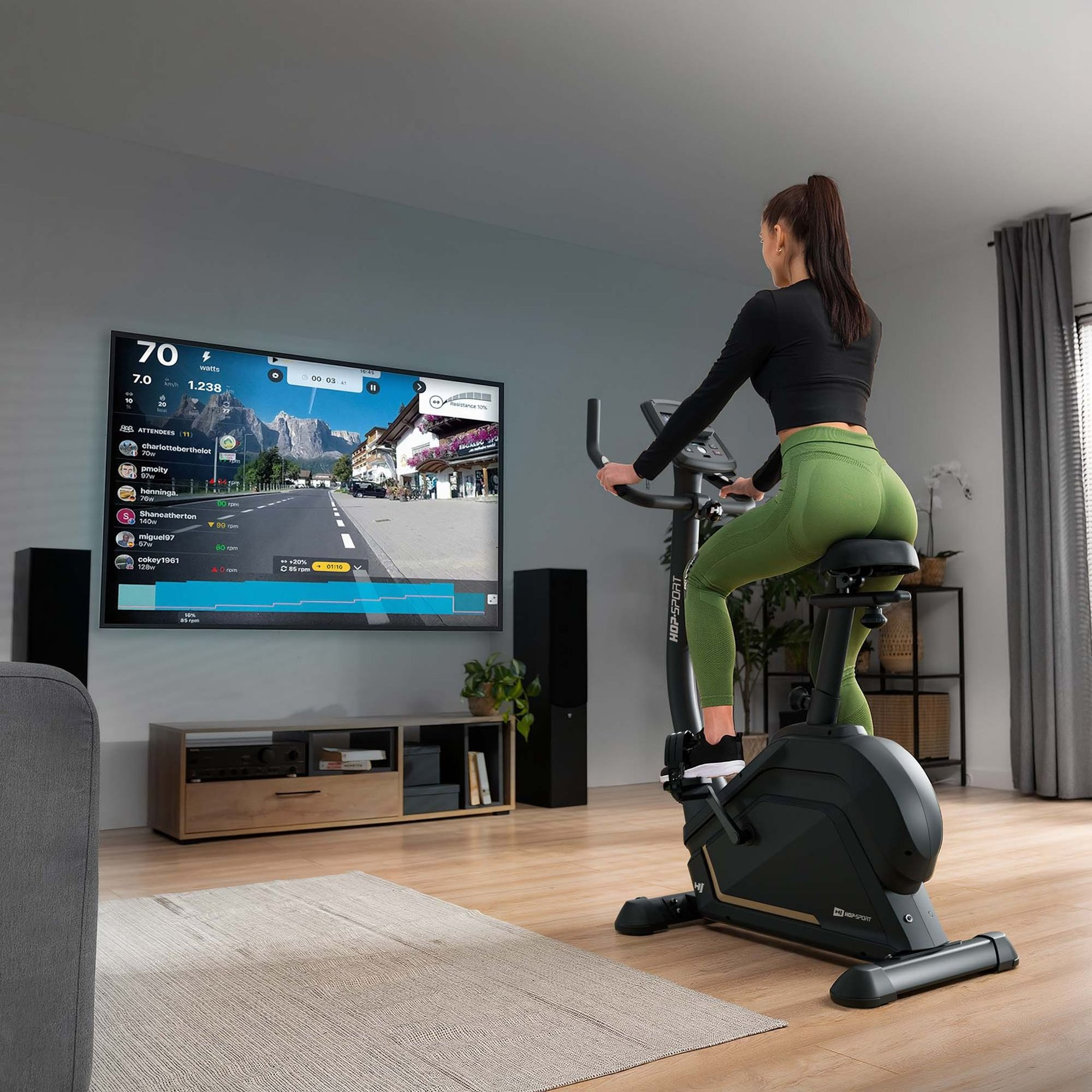 Eine Frau fährt auf einem Heimtrainer, der mit einem großen Bildschirm verbunden ist.