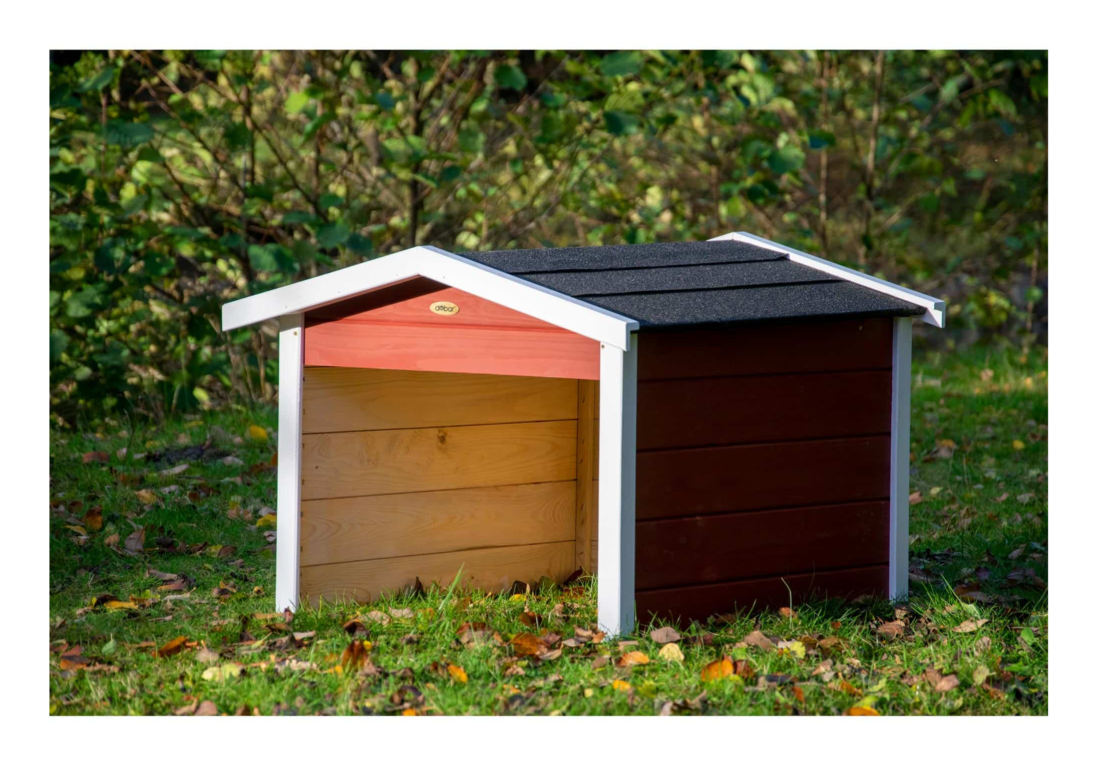Ein rot-braunes Hundehäuschen mit weißem Dachrand steht auf Gras.