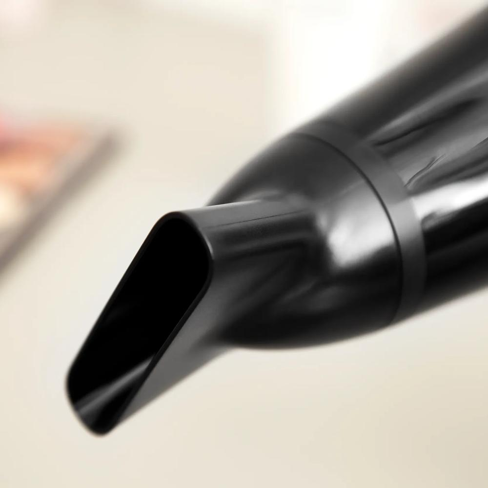 Primo piano di un ugello nero per asciugacapelli su sfondo chiaro.