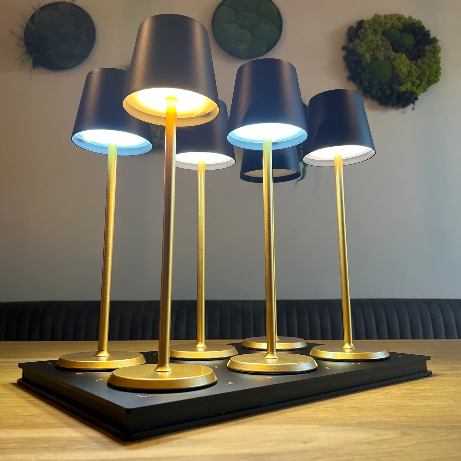 Sechs goldene Tischlampen mit schwarzen Schirmen stehen auf einem schwarzen Tablett.