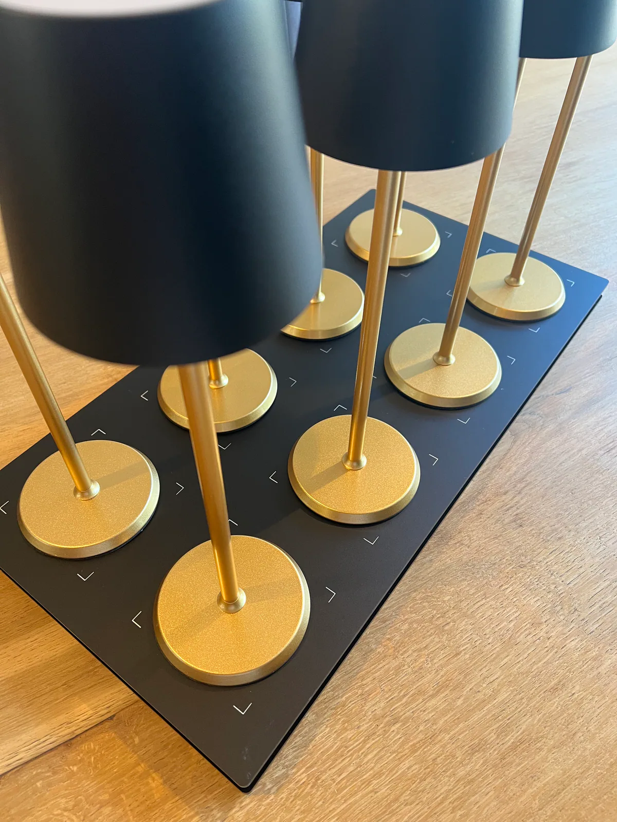 Mehrere schwarze Lampen mit goldenen Ständern stehen auf einer schwarzen Platte.