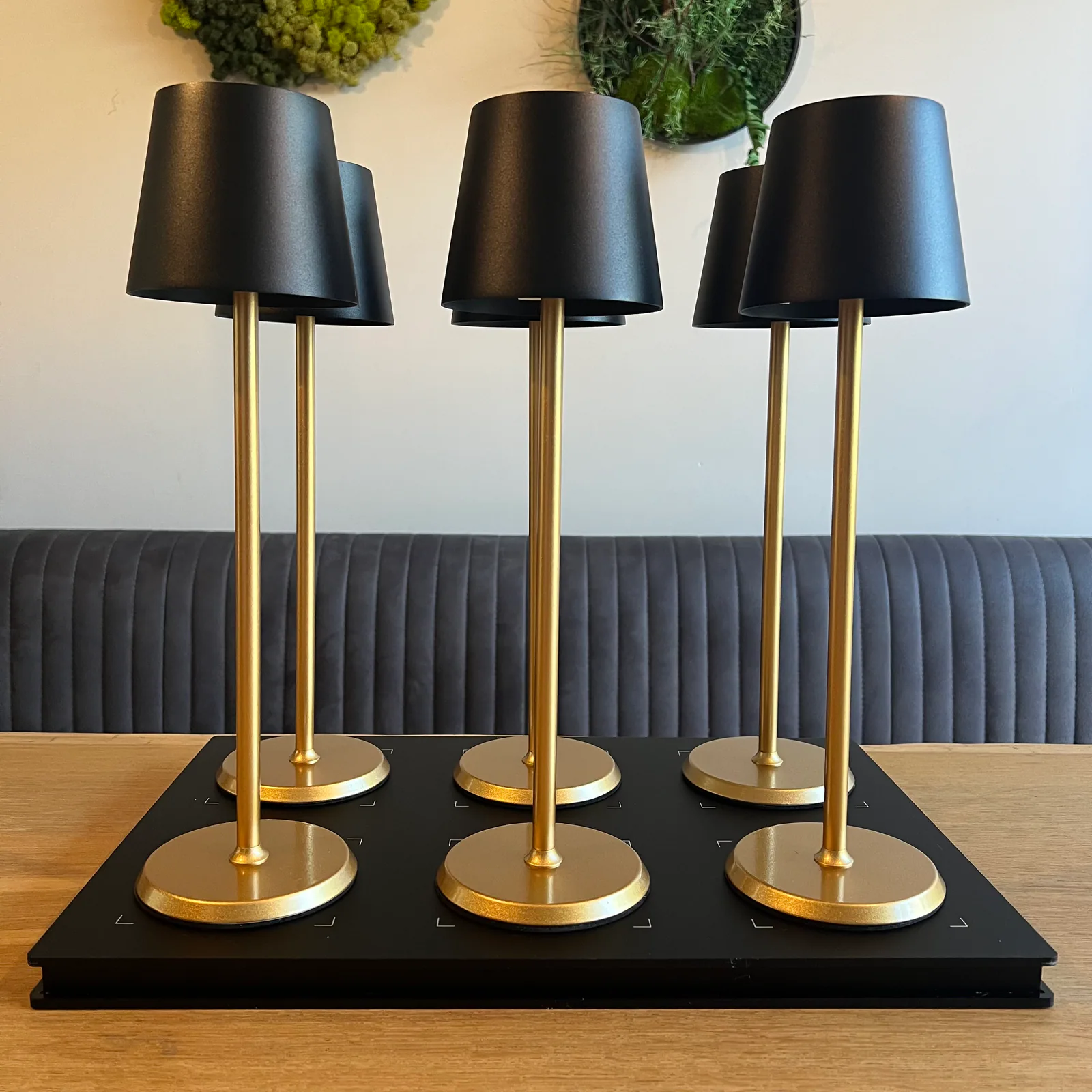 Sechs goldene Lampen mit schwarzen Schirmen auf einem schwarzen Tablett.