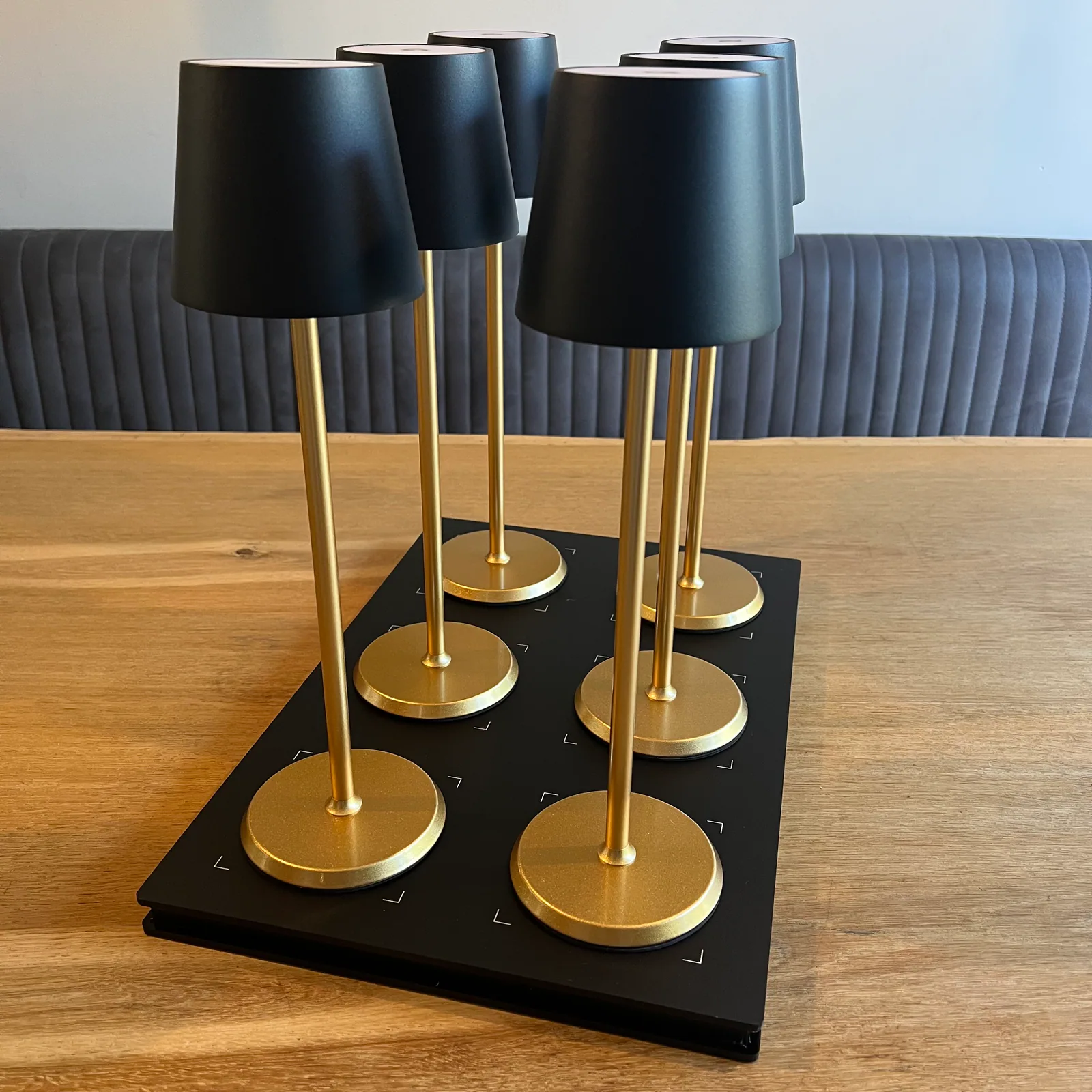 Sechs goldene Lampen mit schwarzen Schirmen auf einem schwarzen Tablett.