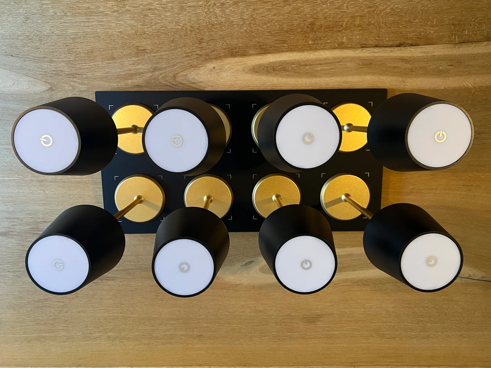 Acht schwarze Lampen mit weißen Lichtern und goldenen Akzenten auf schwarzem Hintergrund.