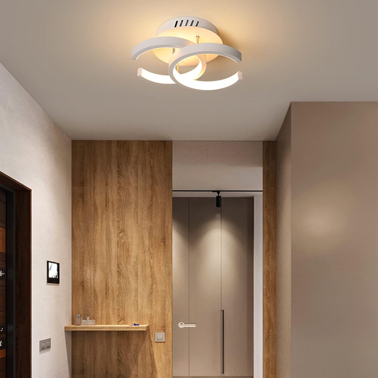 Moderne Deckenleuchte mit drei weißen Ringen über einem Holzboden und Türen.
