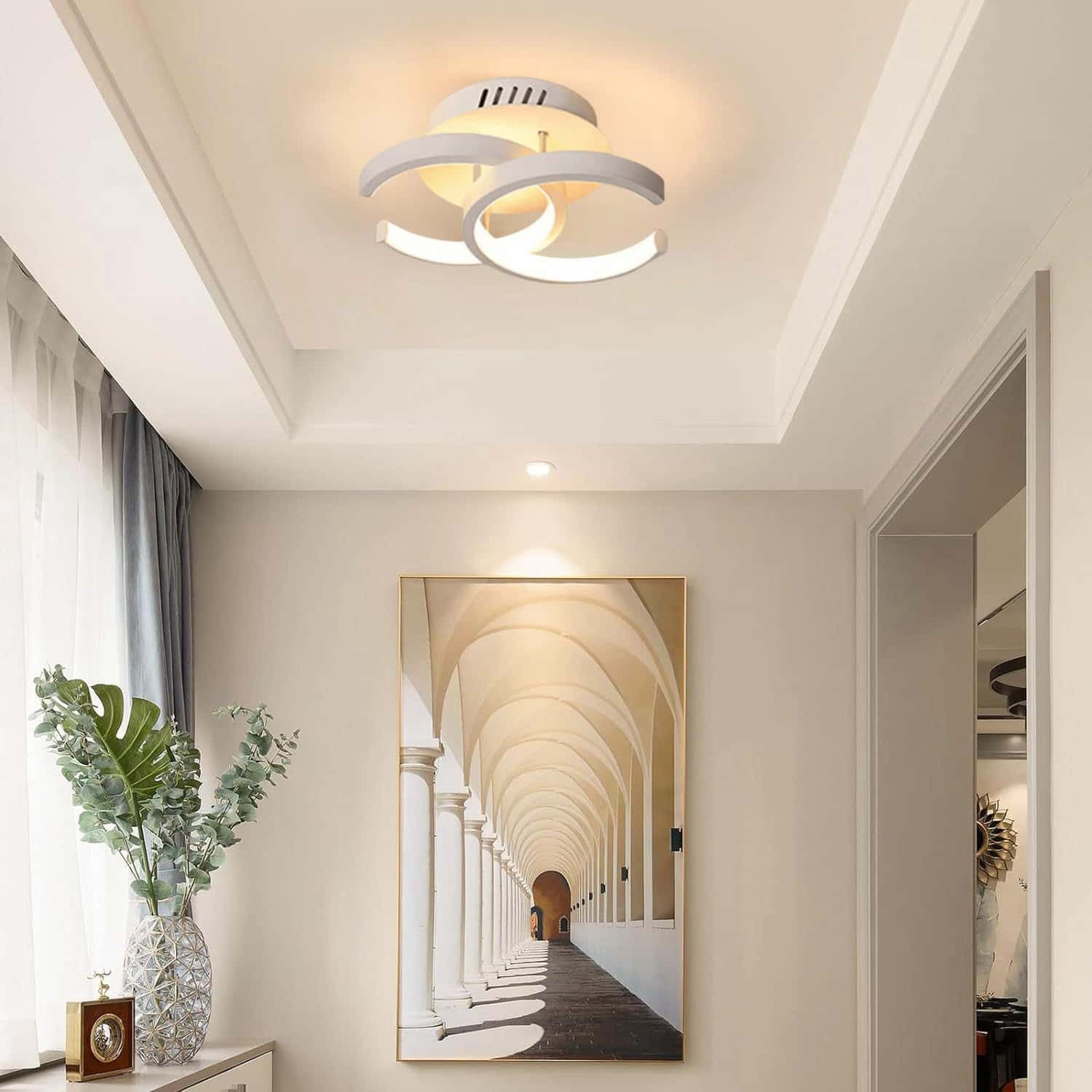 Moderne weiße Deckenleuchte mit drei Ringen über einem gerahmten Gemälde eines Torbogens.