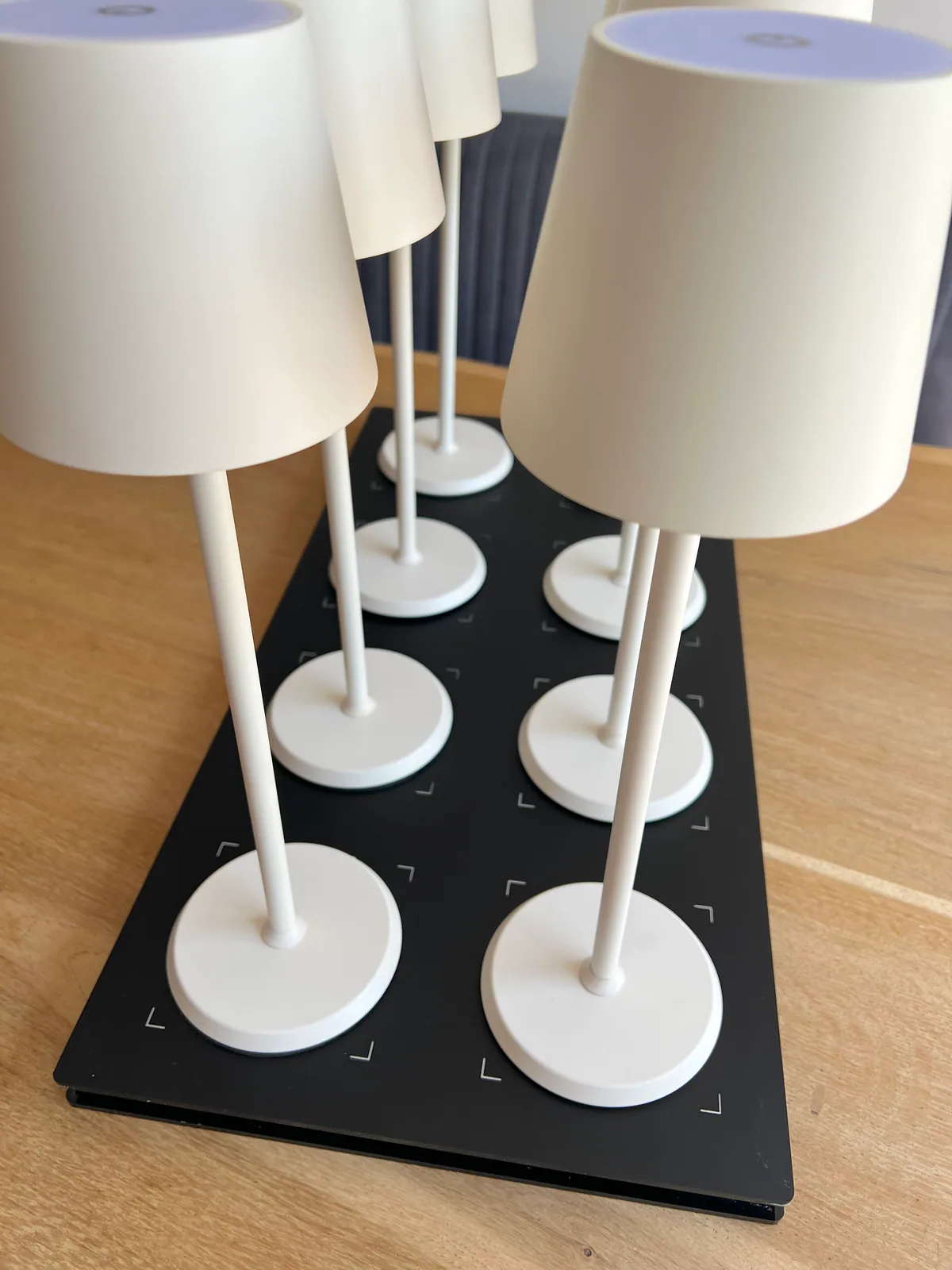 Acht weiße Lampen stehen auf einer schwarzen Ladestation mit Ladeanzeigen.