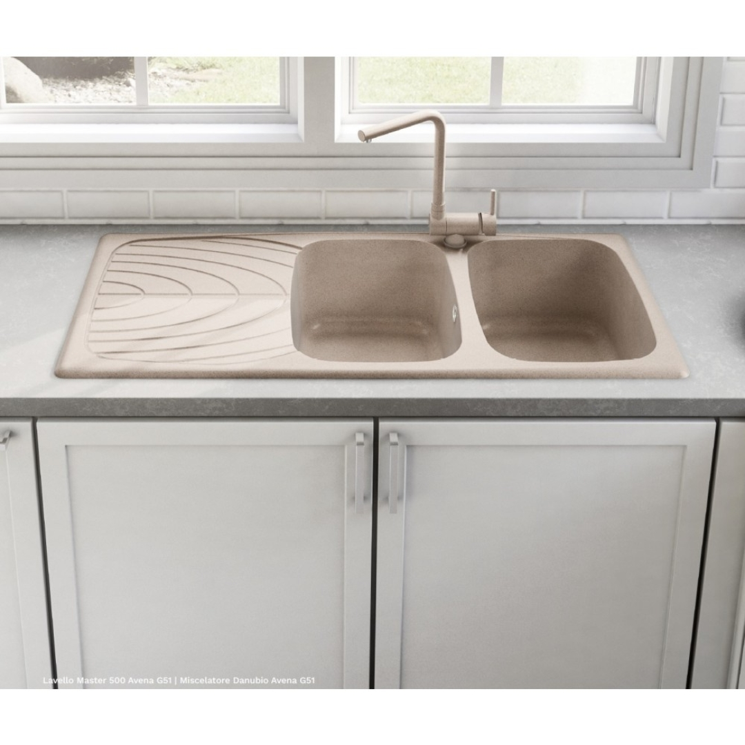 Lavello doppio in composito beige con scivolo e rubinetto sopra mobili bianchi.