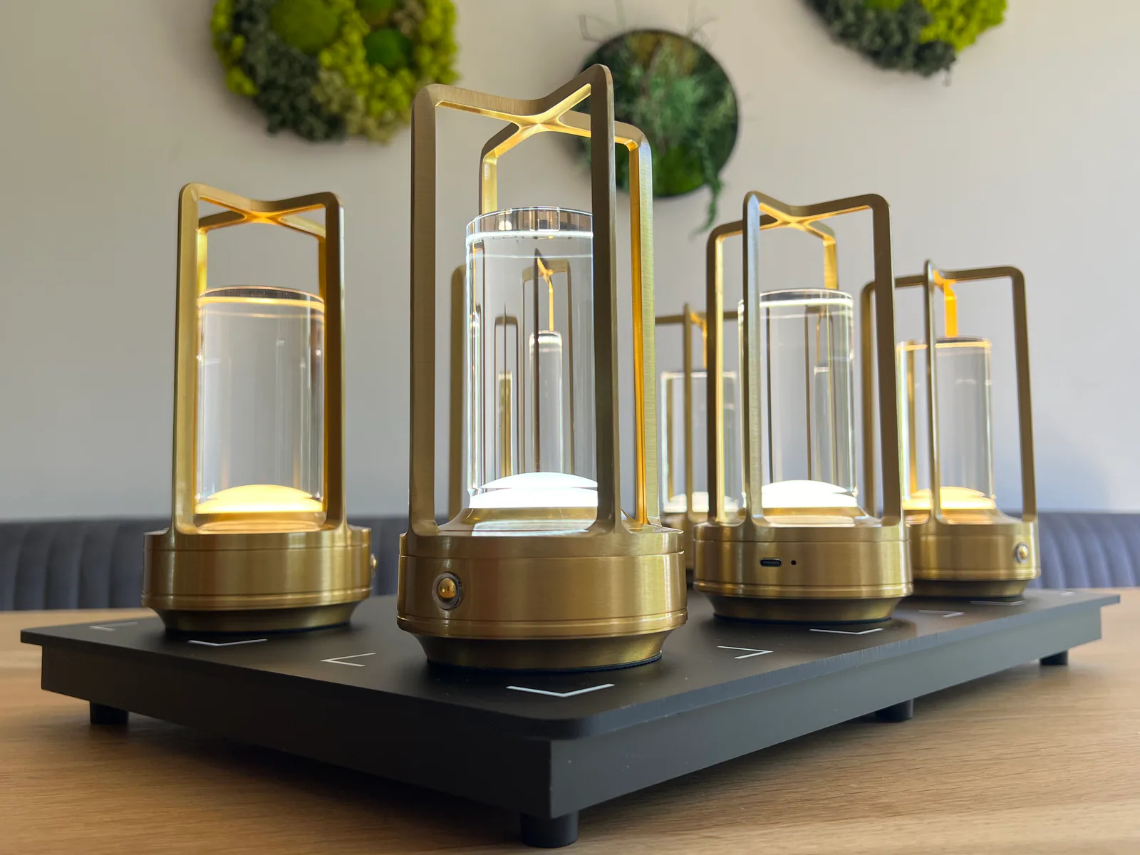 Fünf goldene Laternen mit Glaszylindern auf einer schwarzen Ladeplatte.