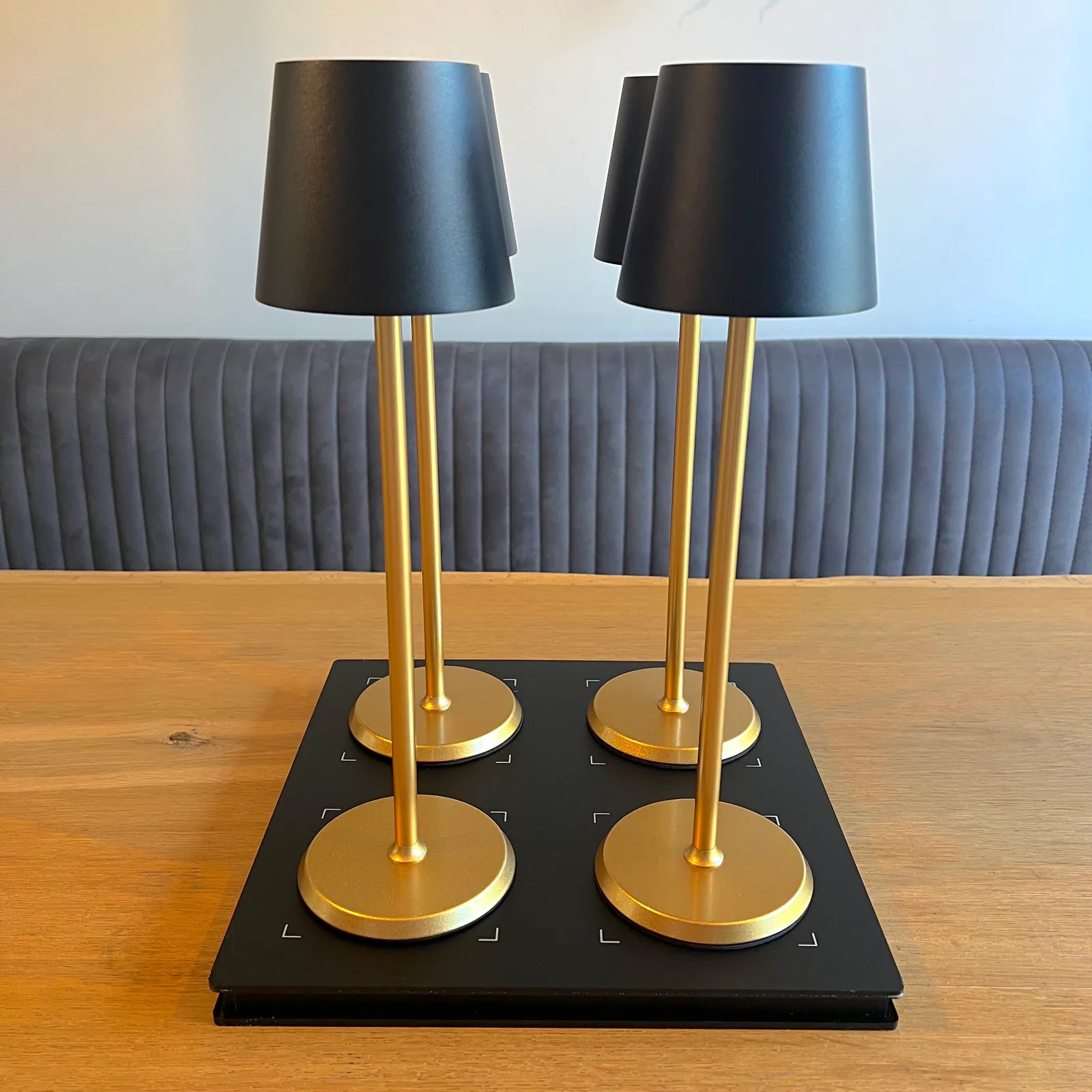 Vier goldene Lampen mit schwarzen Schirmen stehen auf einem Tisch.