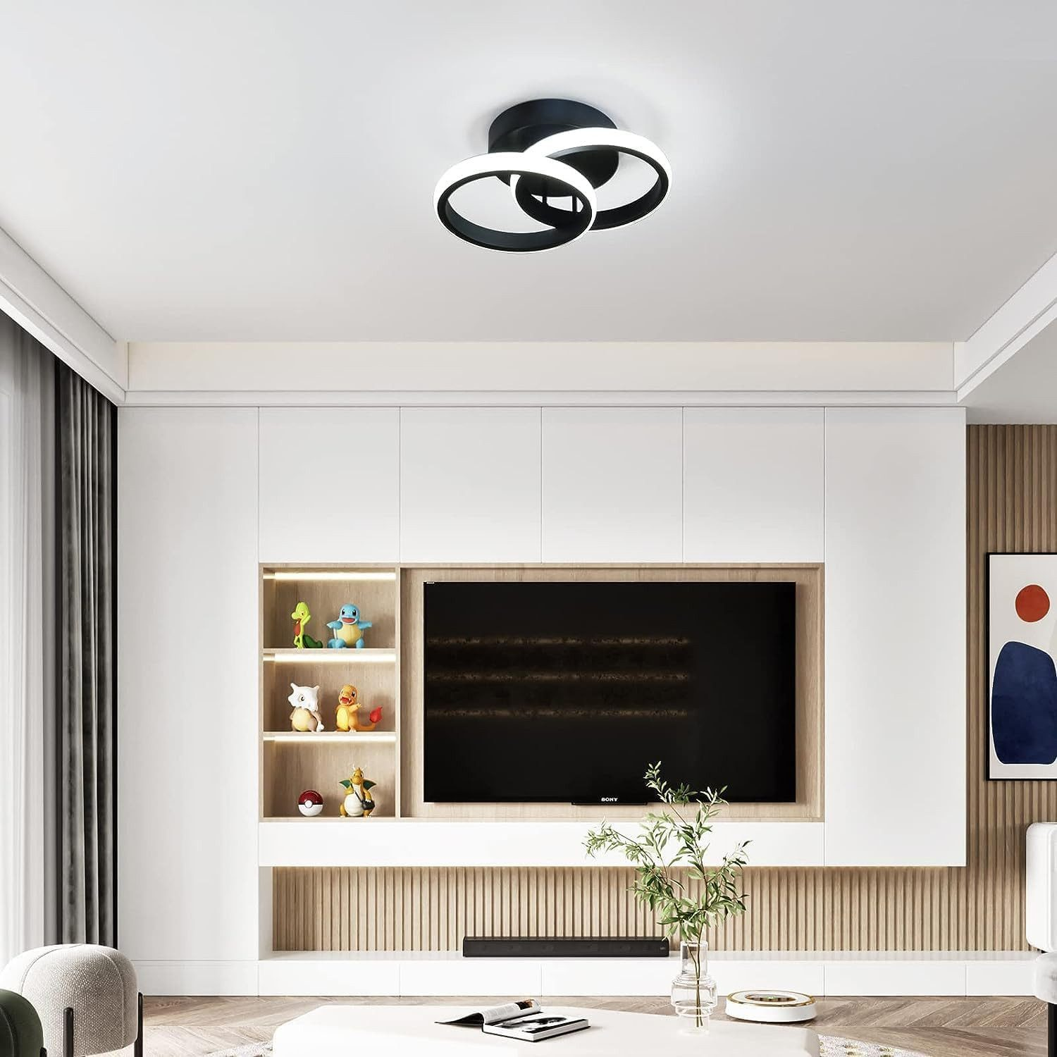 Ein modernes Wohnzimmer mit Einbauschränken, einem Fernseher und Pokémon-Figuren.
