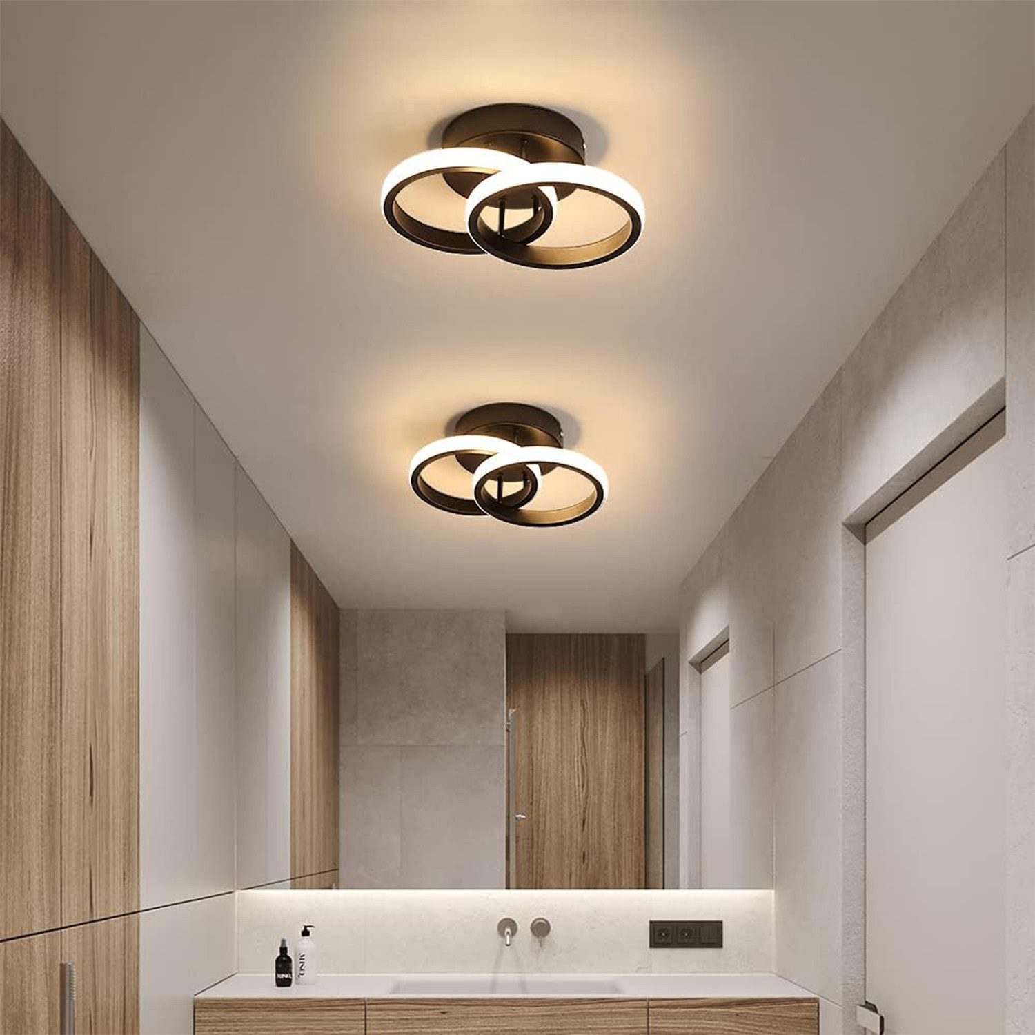 Zwei moderne Deckenleuchten mit Ringen beleuchten einen Flur mit Holzmöbeln.