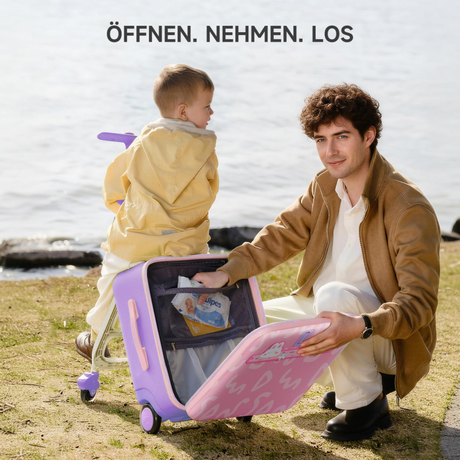 Mann und Kind packen einen lila Koffer am See. Mann gibt Feuchttücher hinein.