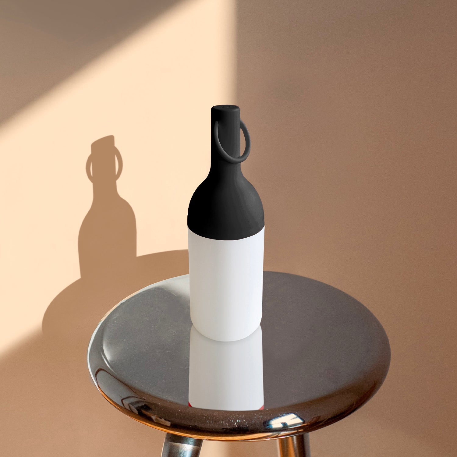 Eine zweifarbige Flasche (schwarz-weiß) steht auf einem runden Metallhocker.