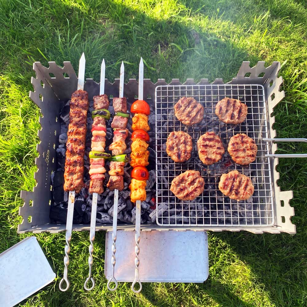 Çimenlerin üzerinde kömürlü mangalda pişen et şişleri ve burger köfteleri.