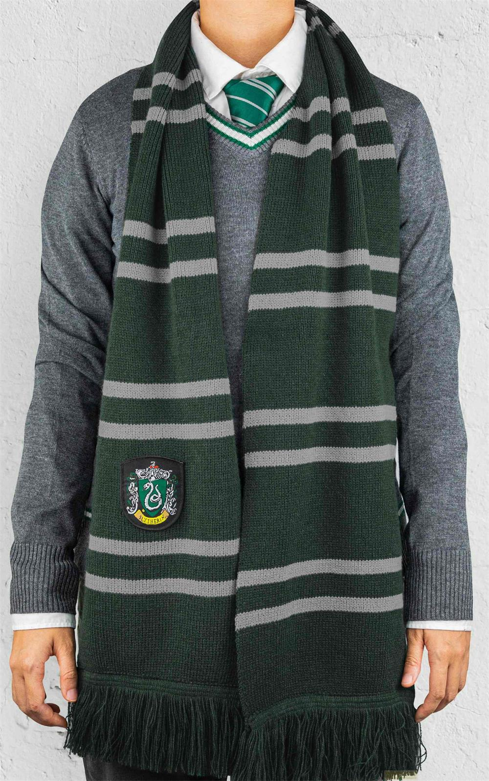 Una persona indossa un maglione grigio, camicia bianca, cravatta verde e sciarpa a strisce.