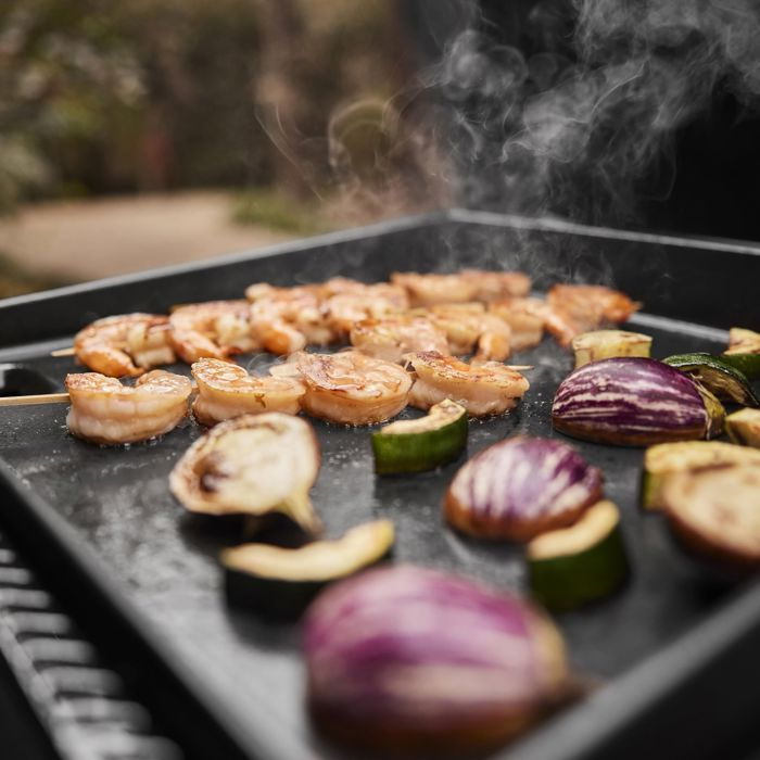 Garnalen en aubergines grillen, met opstijgende rook.