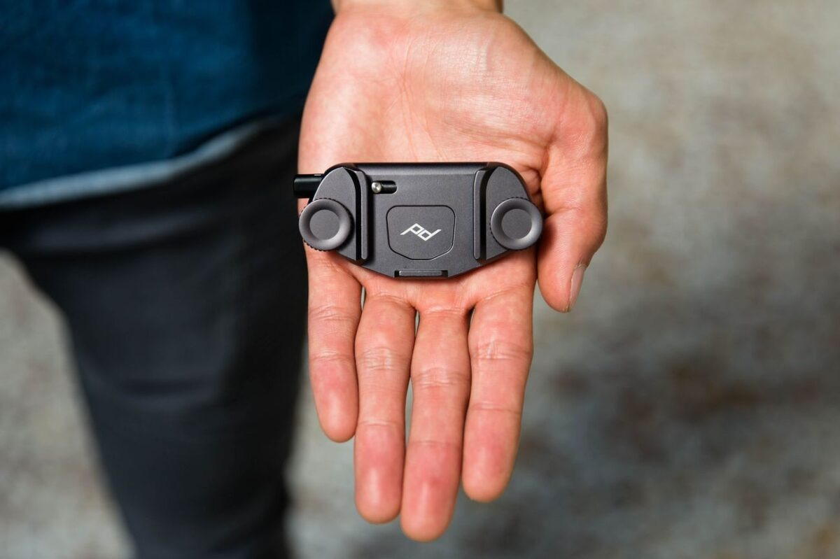 Una mano tiene un piccolo accessorio nero con due ruote e un logo PD.
