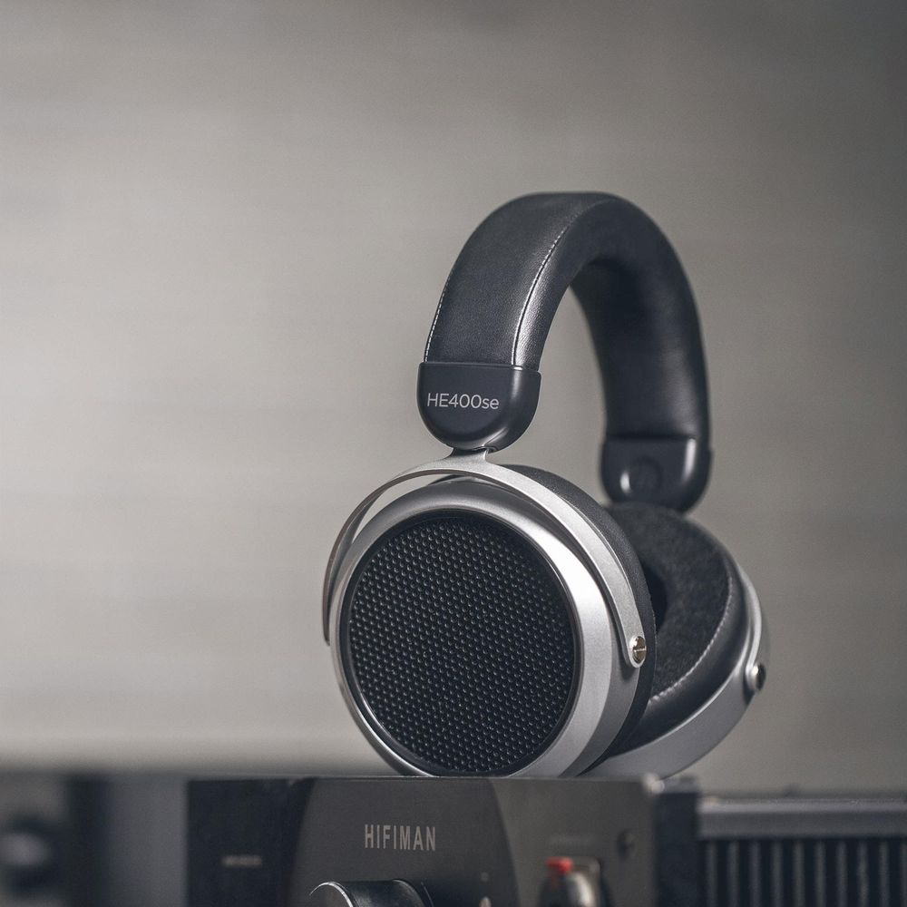 Auriculares plateados y negros HE400se con diadema de cuero descansan sobre Hifiman.