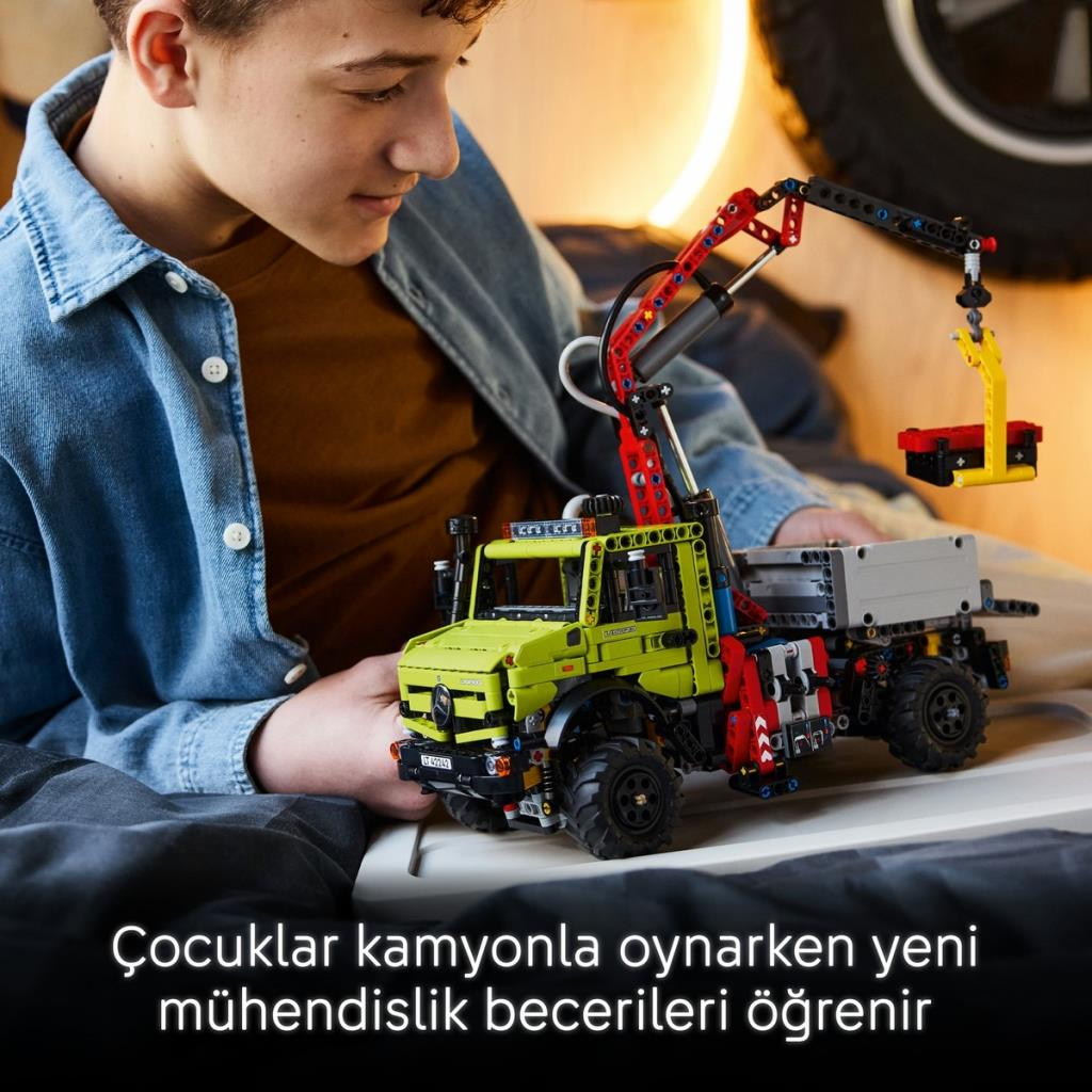 Bir çocuk vinçli sarı bir oyuncak kamyon inşa ediyor.