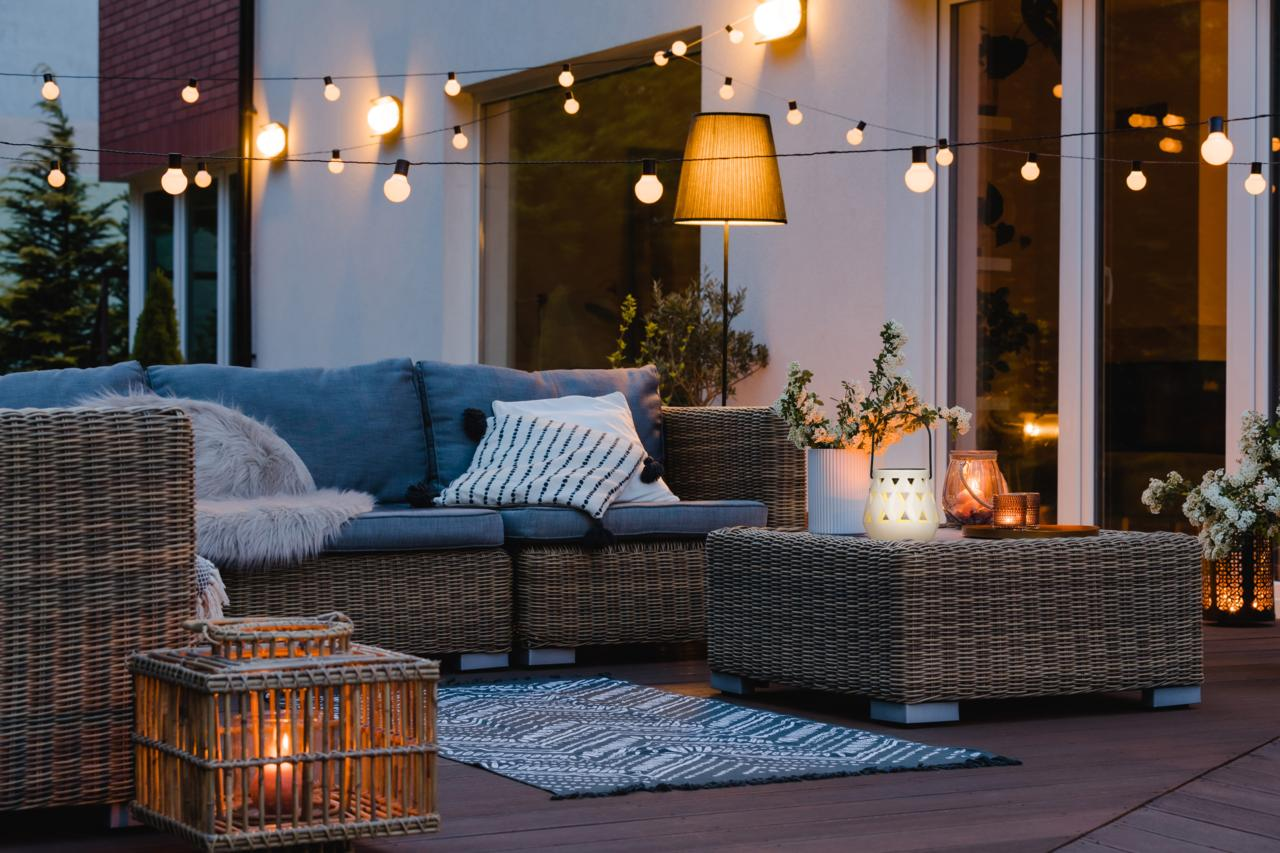 A cozy patio with seating, string lights, and lanterns at night.