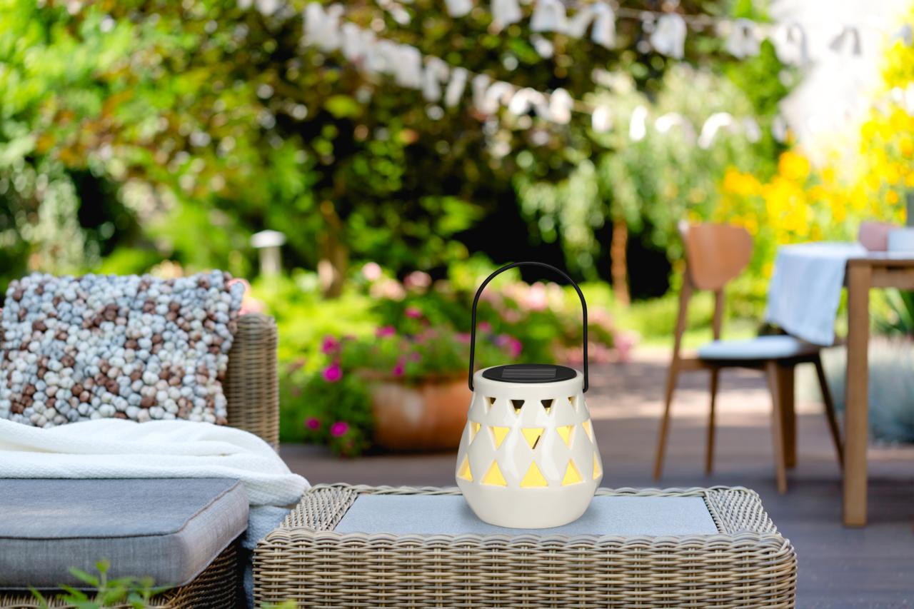 A white lantern with geometric patterns sits on an outdoor table.