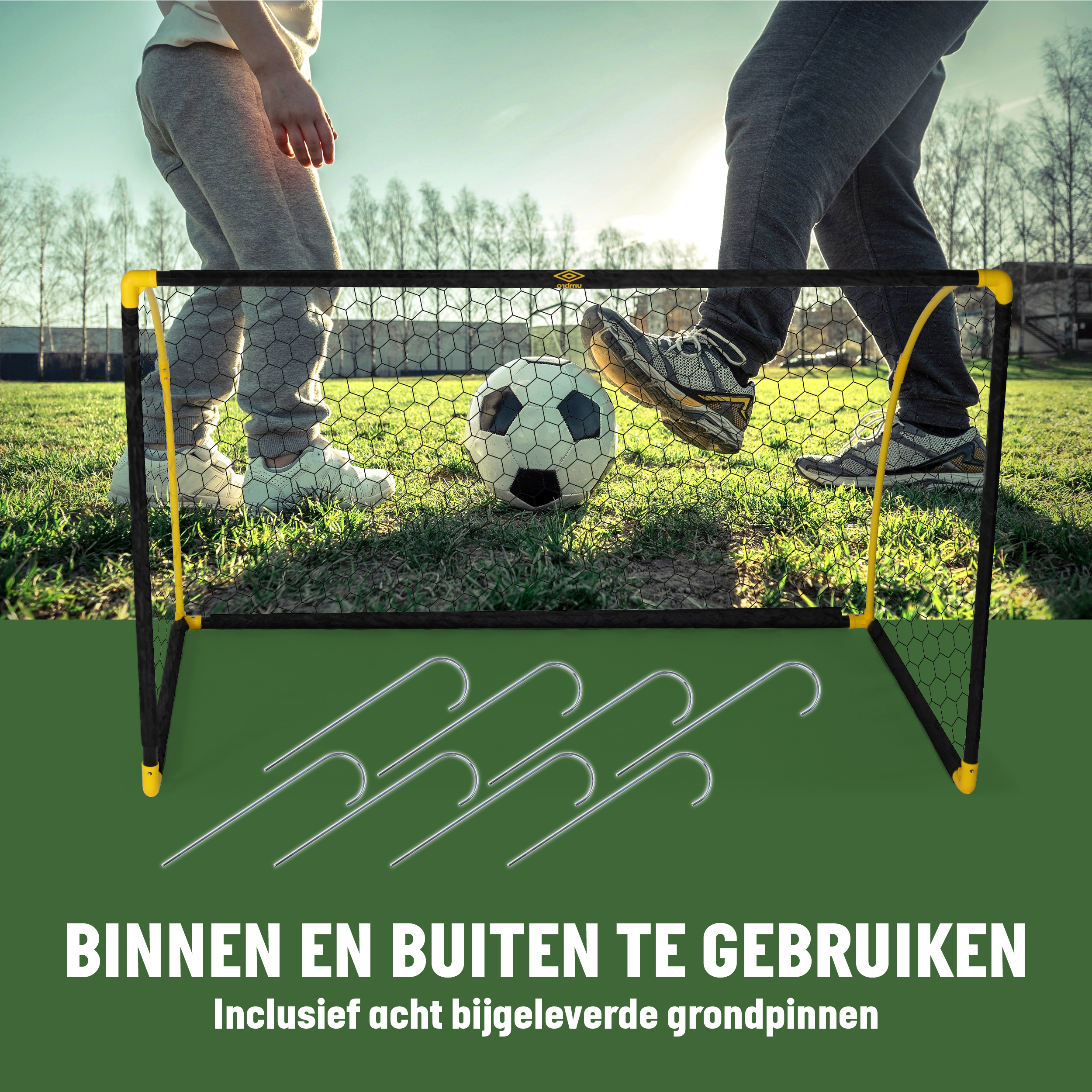 Kinder spielen Fußball an einem Tor mit Ball und Haken im Gras.
