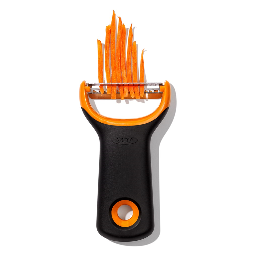 Un pelapatate nero e arancione con carote a julienne.