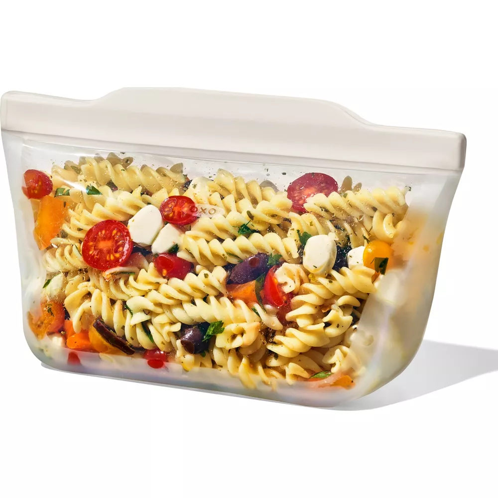 Spiralnudelsalat mit Tomaten, Mozzarella und Oliven in einer durchsichtigen Tasche.