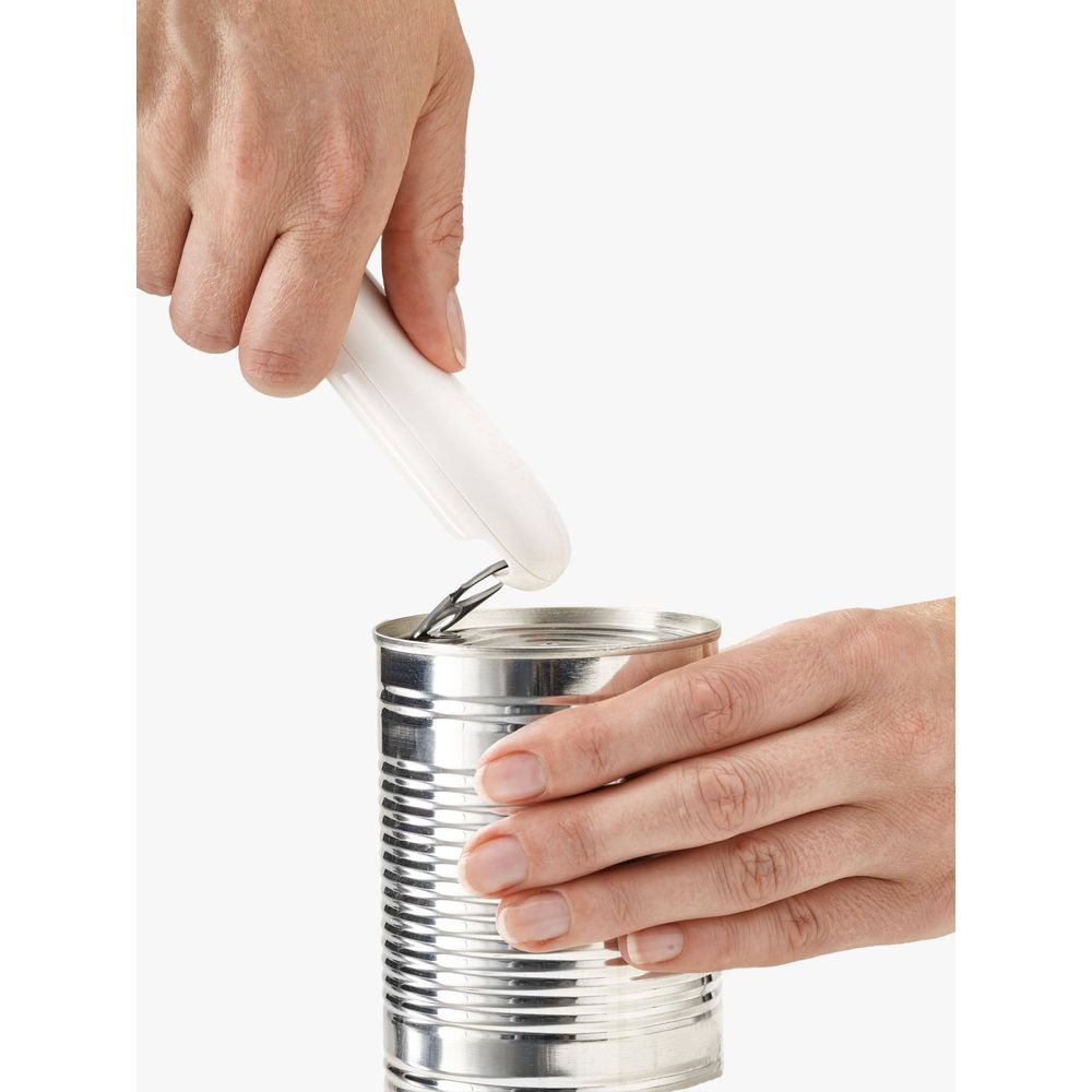 Manos abriendo una lata plateada con un abrelatas blanco.