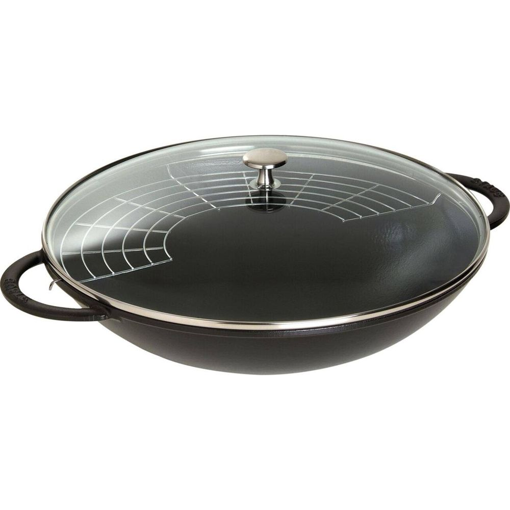 Ein schwarzer Gusseisen-Wok mit Glasdeckel und Drahteinlage.