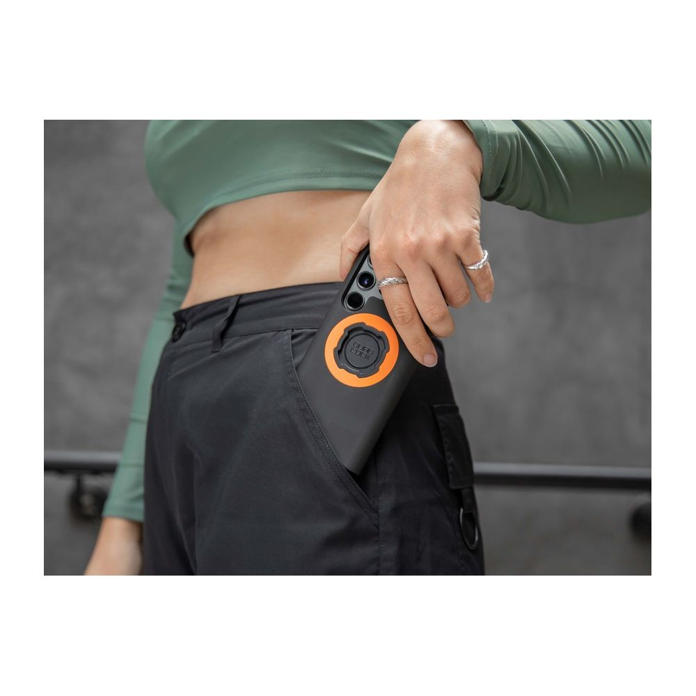 Eine Person steckt ein Handy mit orangem Ring in eine Cargohose.