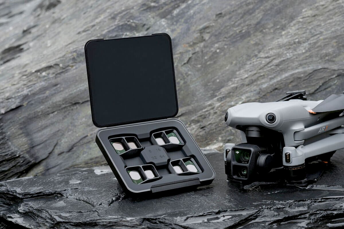 Drone DJI Air 3 grigio con set di filtri per obiettivi su rocce bagnate.