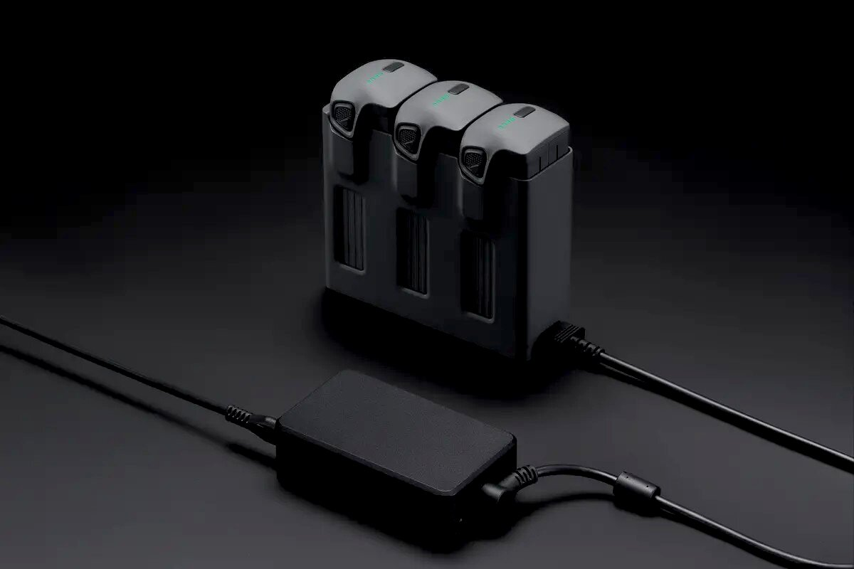 Tre batterie grigie in un hub di ricarica, collegate a un adattatore.