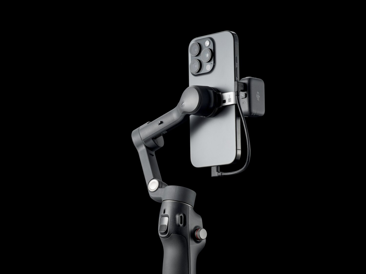 Smartfon jest zamontowany na stabilizatorze gimbala z czarnym tłem.